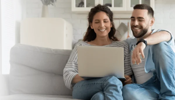 Happy Couple Using Laptop on Couch PNG